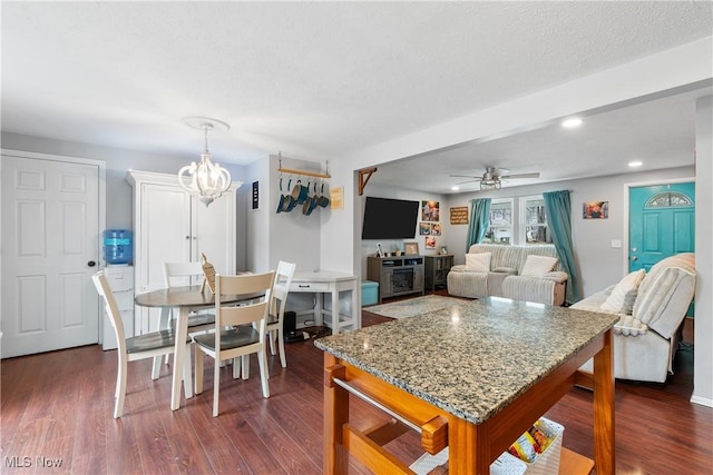 dining space featuring ceiling fan with notable chandelier, dark hardwood / wood-style floors, and a textured ceiling