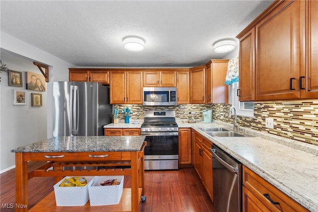 kitchen featuring sink, light stone counters, tasteful backsplash, appliances with stainless steel finishes, and dark hardwood / wood-style floors