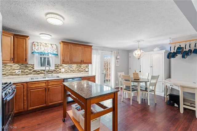 kitchen featuring appliances with stainless steel finishes, tasteful backsplash, sink, hanging light fixtures, and dark wood-type flooring