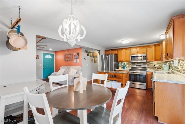 dining area featuring sink, ceiling fan with notable chandelier, and dark hardwood / wood-style flooring