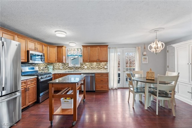 kitchen featuring pendant lighting, stainless steel appliances, dark wood-type flooring, and sink