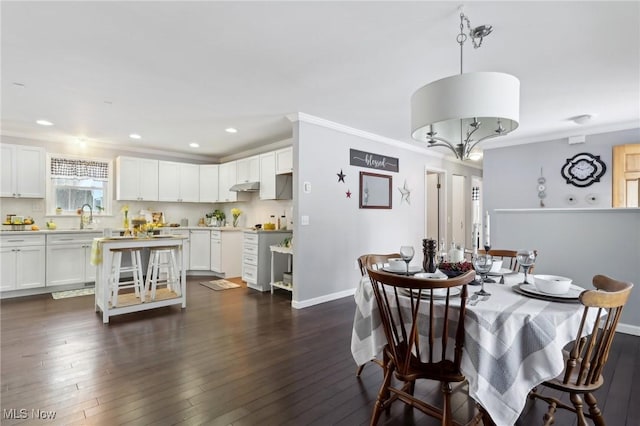 dining space with dark hardwood / wood-style flooring, sink, and ornamental molding