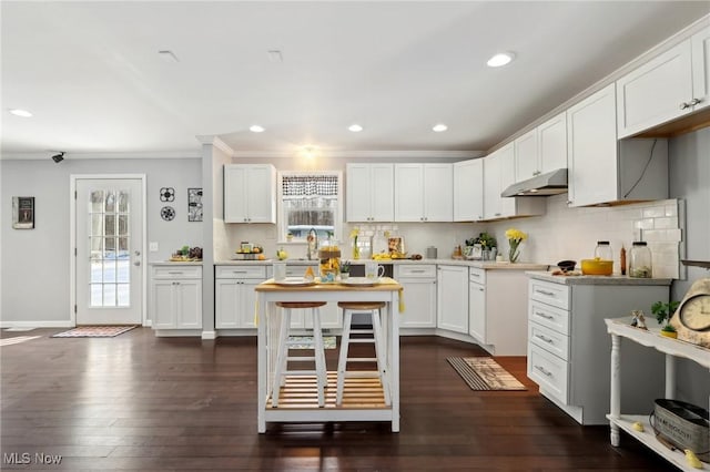 kitchen featuring dark wood-type flooring, sink, white cabinetry, crown molding, and decorative backsplash