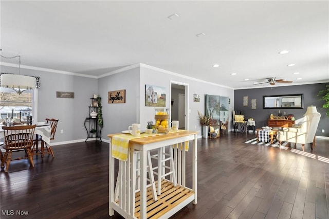 kitchen with dark wood-type flooring, ceiling fan, crown molding, and a breakfast bar