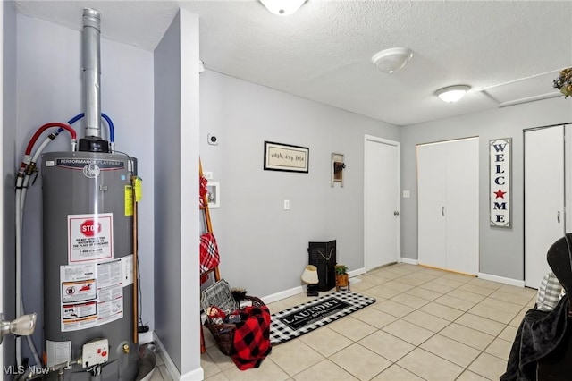 foyer entrance with a textured ceiling, water heater, and light tile patterned floors