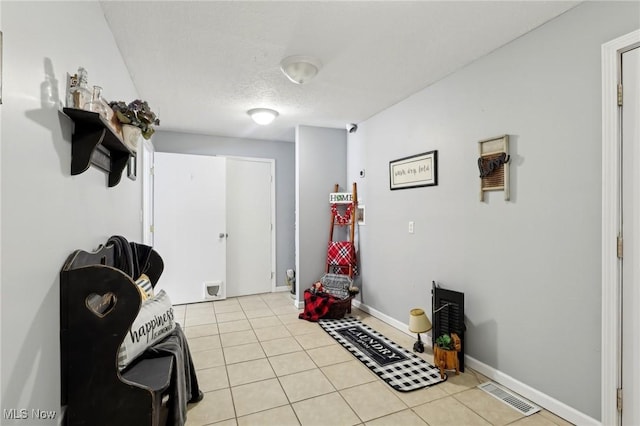 misc room featuring light tile patterned flooring and a textured ceiling