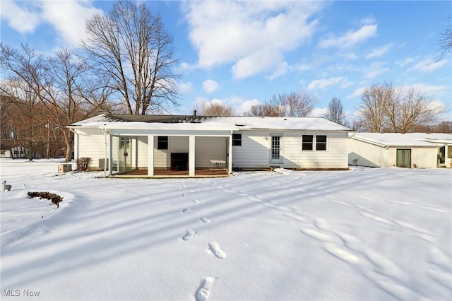 snow covered rear of property featuring covered porch