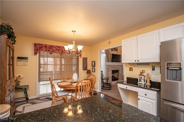 kitchen featuring pendant lighting, dark stone countertops, white cabinets, a chandelier, and stainless steel refrigerator with ice dispenser