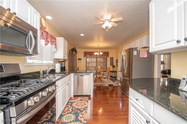 kitchen featuring decorative light fixtures, white cabinetry, dark stone counters, stainless steel appliances, and dark wood-type flooring