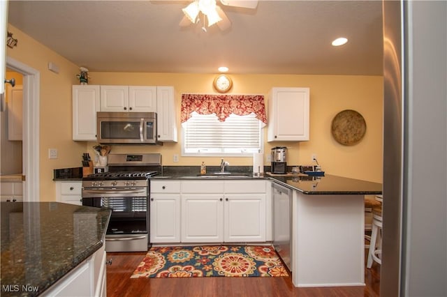 kitchen featuring white cabinetry, appliances with stainless steel finishes, sink, and dark stone counters