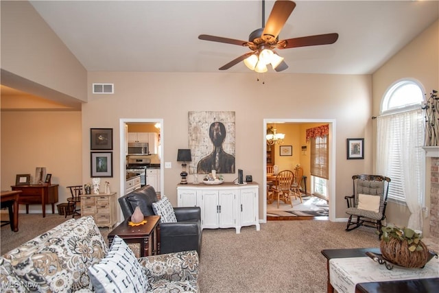 carpeted living room with ceiling fan with notable chandelier