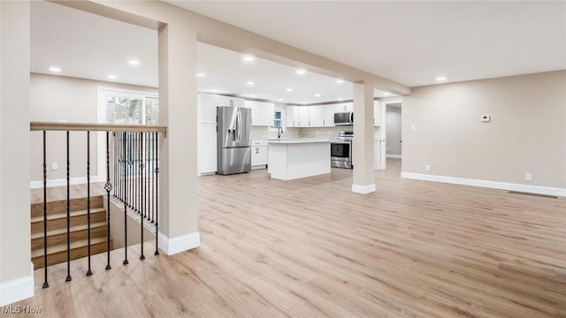 unfurnished living room featuring sink and light wood-type flooring