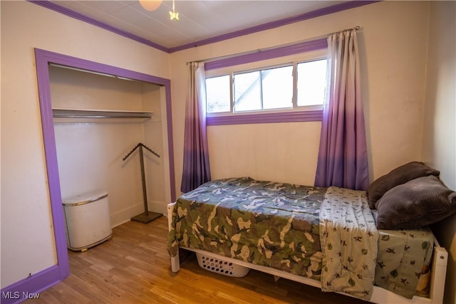 bedroom featuring crown molding, a closet, and light wood-type flooring