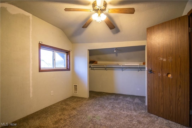 unfurnished bedroom featuring lofted ceiling, carpet flooring, ceiling fan, and a closet