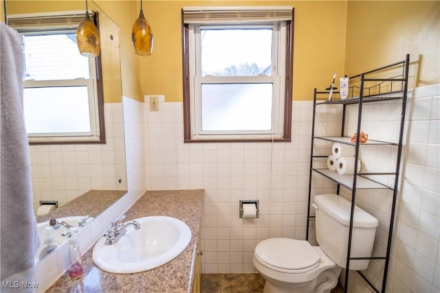 bathroom featuring vanity, toilet, tile walls, and a wealth of natural light