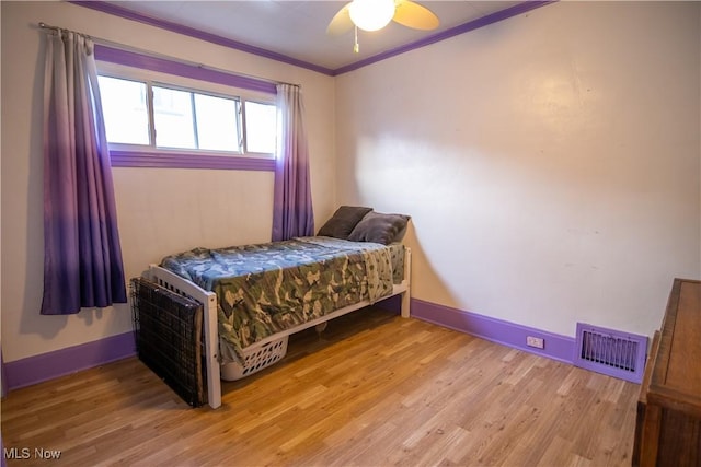 bedroom with crown molding, wood-type flooring, and ceiling fan