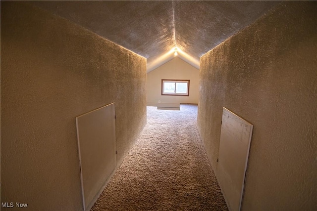 hall with vaulted ceiling and carpet