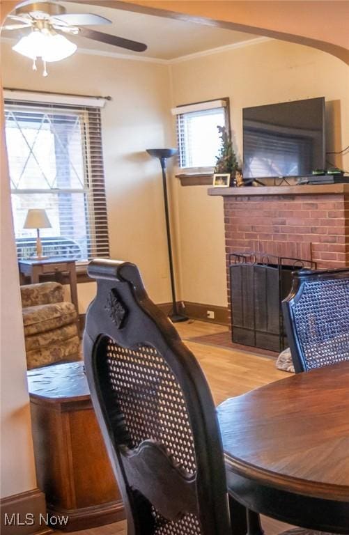 interior space with crown molding, ceiling fan, light hardwood / wood-style floors, and a brick fireplace