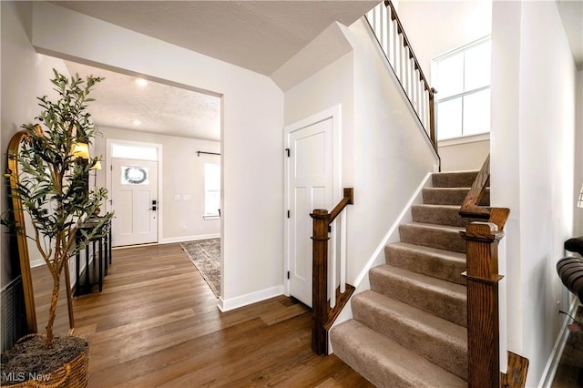 foyer featuring dark wood-style floors, stairway, and baseboards