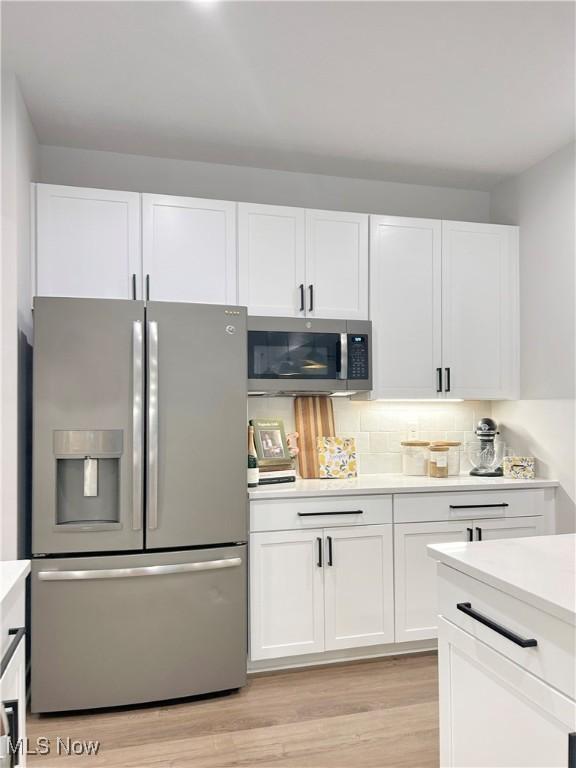 kitchen featuring light wood finished floors, appliances with stainless steel finishes, white cabinetry, and light countertops