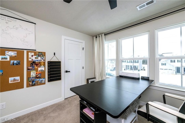 office with visible vents, baseboards, light colored carpet, and a healthy amount of sunlight