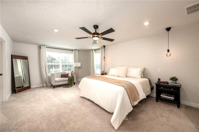 bedroom featuring light carpet, visible vents, a textured ceiling, and baseboards