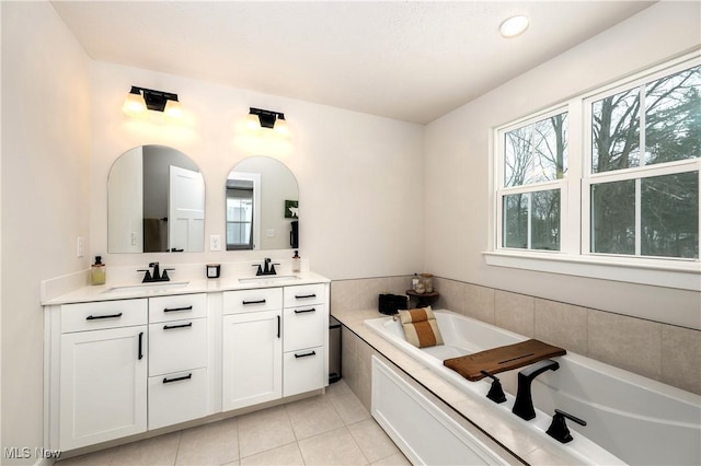 bathroom with tile patterned floors, a garden tub, double vanity, and a sink