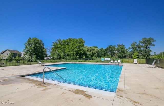 community pool with a patio area and fence