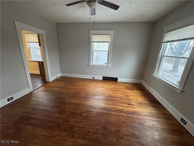 spare room with dark wood-type flooring, a healthy amount of sunlight, and a textured ceiling