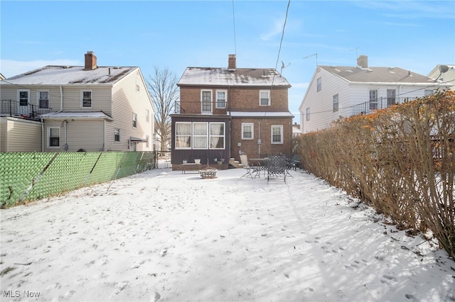 snow covered rear of property featuring an outdoor fire pit