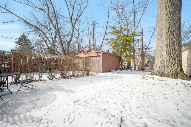 yard covered in snow with a garage and an outdoor structure