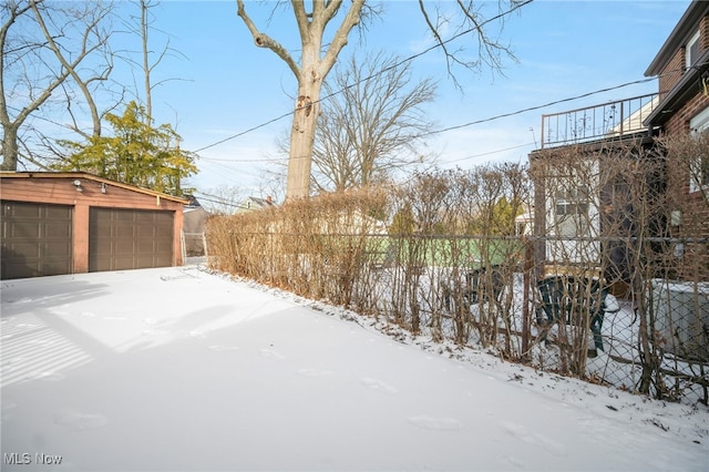 snowy yard featuring an outbuilding and a garage