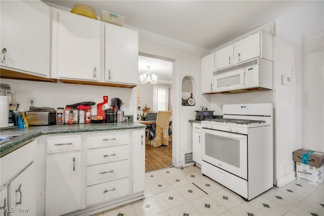 kitchen with crown molding, a chandelier, white cabinets, and white appliances