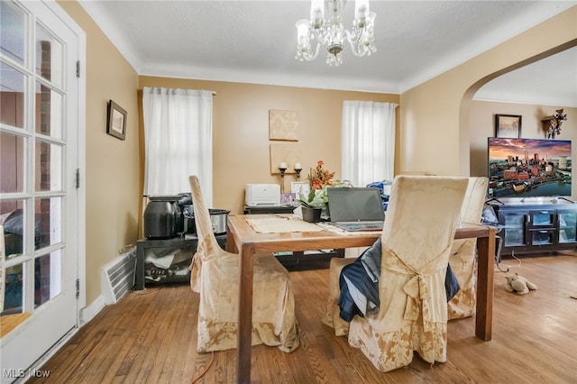 dining area with crown molding, light hardwood / wood-style flooring, and a notable chandelier