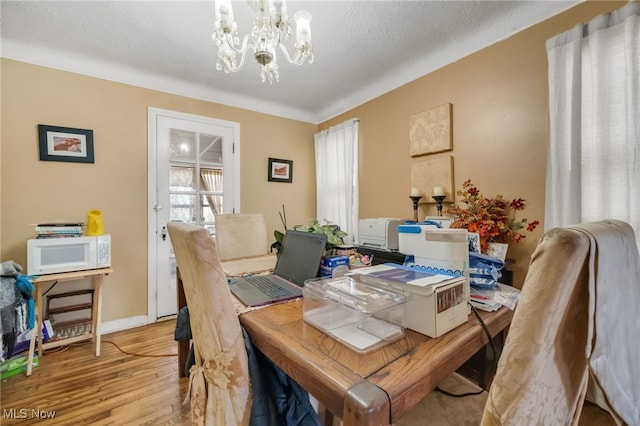 dining room featuring a notable chandelier, a textured ceiling, and light wood-type flooring