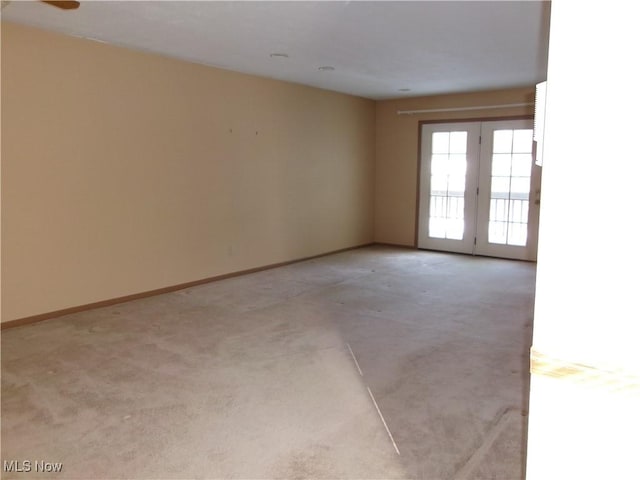 empty room featuring light carpet and baseboards