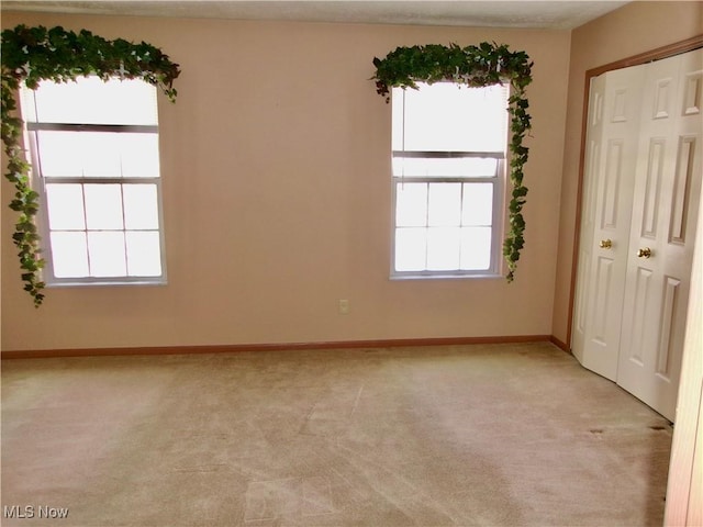 unfurnished room with light carpet and baseboards