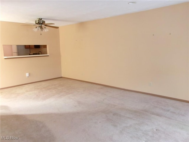 carpeted spare room with a ceiling fan and baseboards