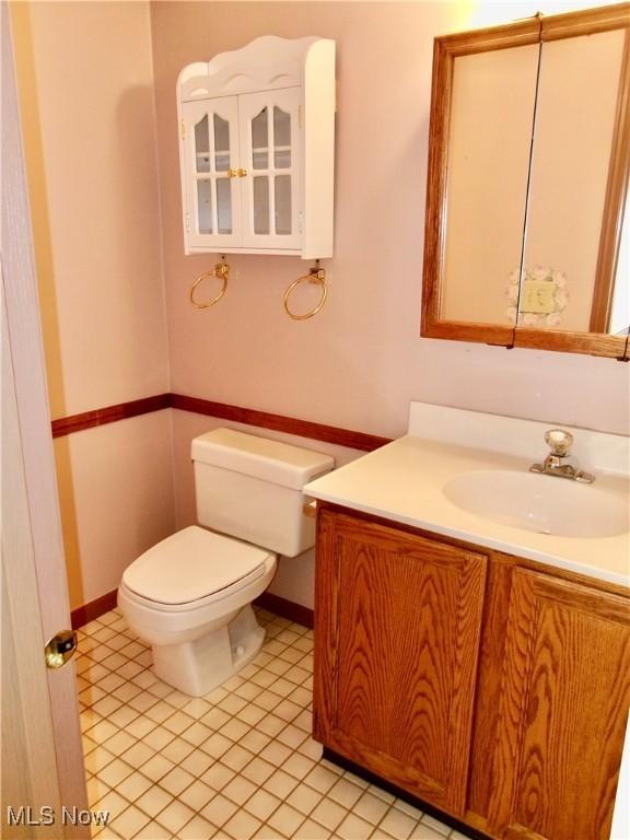 bathroom featuring baseboards, vanity, toilet, and tile patterned floors