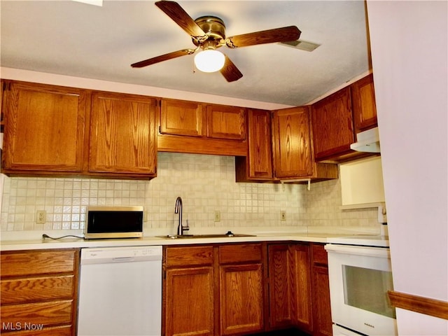 kitchen featuring light countertops, white appliances, brown cabinetry, and a sink