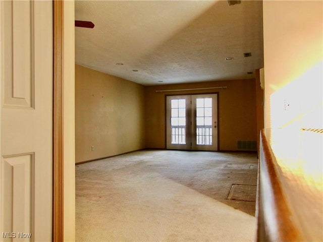 unfurnished room with french doors, visible vents, and light colored carpet