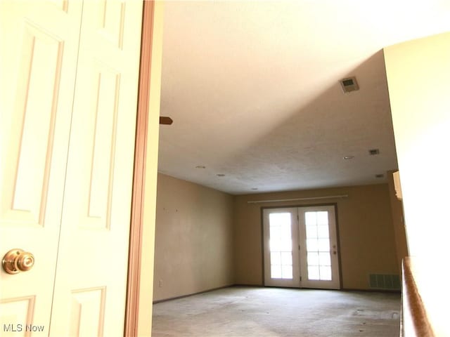 spare room featuring visible vents, french doors, and light colored carpet