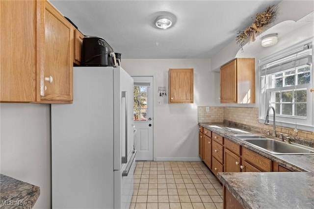 kitchen with white refrigerator, light tile patterned floors, sink, and backsplash