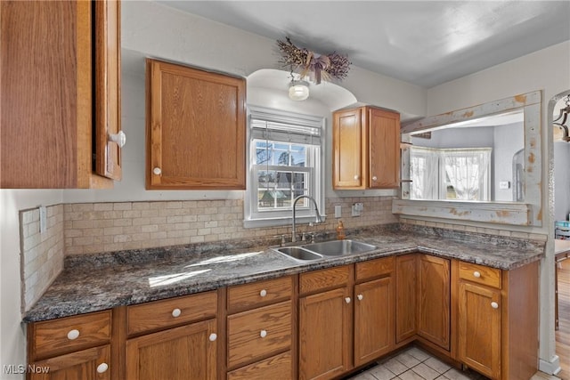 kitchen with tasteful backsplash, plenty of natural light, sink, and dark stone countertops