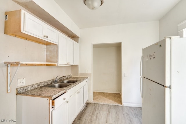 kitchen featuring sink, light wood-type flooring, white cabinets, and white fridge