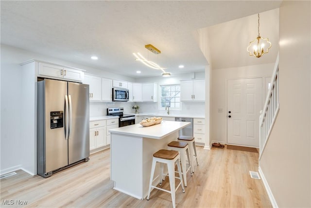 kitchen featuring stainless steel appliances, a center island, pendant lighting, and white cabinets