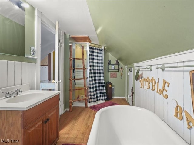 bathroom featuring vanity, vaulted ceiling, hardwood / wood-style floors, and a tub