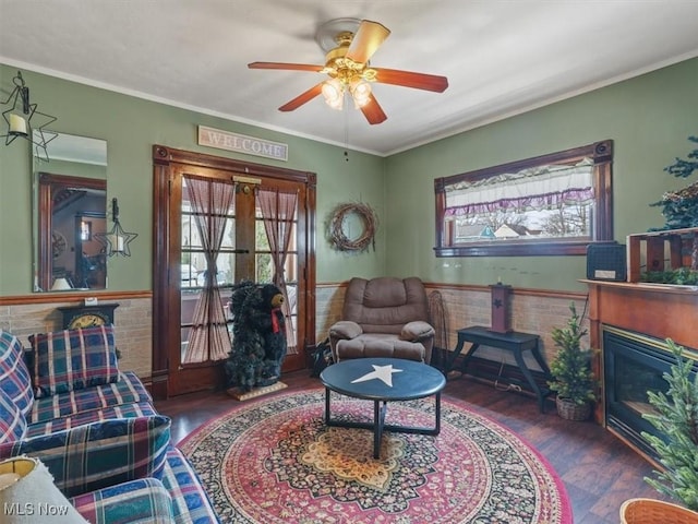 living room with dark wood-type flooring, ornamental molding, and ceiling fan