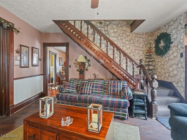 living room featuring ceiling fan, wood-type flooring, and a textured ceiling