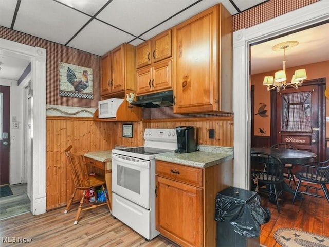 kitchen with white appliances, a notable chandelier, hanging light fixtures, and light wood-type flooring